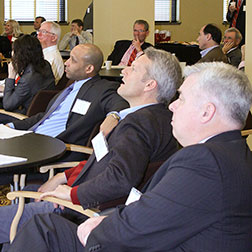 Image of people listening to a speaker in a large meeting room.